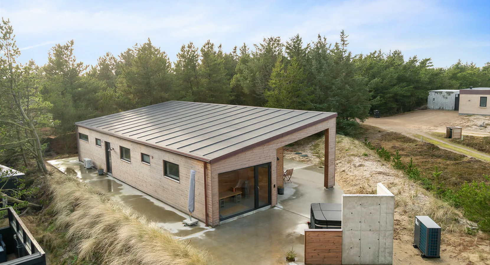 Nybygget sommerhus set fra luften med støbt betonterrasse hele vejen rundt om huset